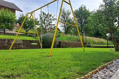 a swing set in a yard with green grass at Studio Sofia in Rakek