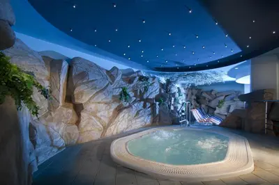a hot tub in a room with a rock wall at Lux Chalet - Sauna and Hot Tub in Topolšica