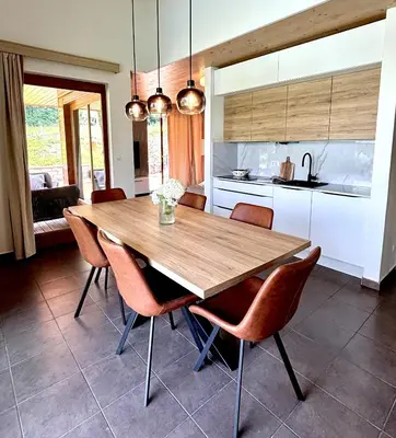 a kitchen with a wooden table and chairs at Lux Chalet - Sauna and Hot Tub in Topolšica