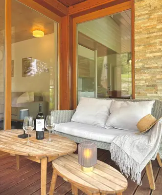 a couch on a porch with two tables and wine glasses at Lux Chalet - Sauna and Hot Tub in Topolšica