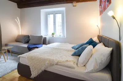 a bedroom with a bed and a couch and a window at Ljubljana Center Apartments in Ljubljana