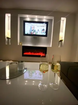 two glasses of wine sitting on a table with a tv at Black & White Hideaway with garage in Ljubljana