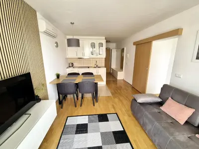 a living room and kitchen with a couch and a table at Apartmaji PANONIA 