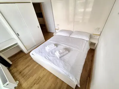 a small bedroom with a bed with white sheets and pillows at Apartmaji PANONIA 