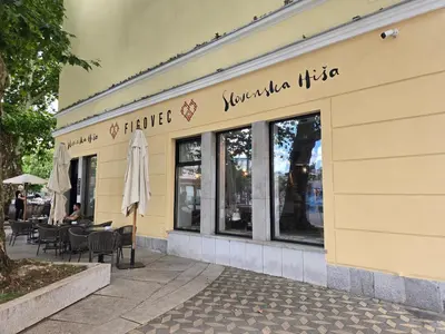 a yellow building with a restaurant with tables and chairs at Neptun apartment in Ljubljana