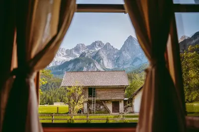 a window view of a house with mountains in the background at Cozy Alpine House in Gozd Martuljek