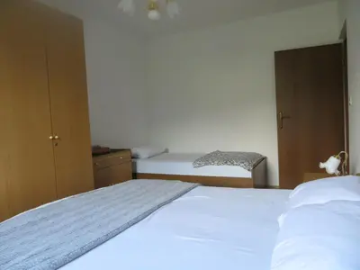 a bedroom with a white bed and a chair at Sobe Orešje in Črniče