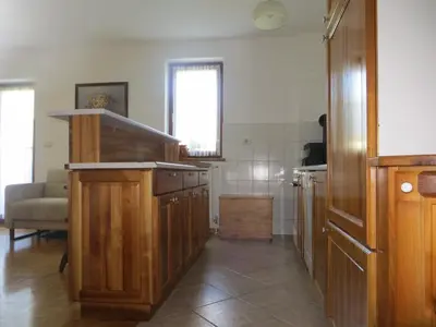 a kitchen with wooden cabinets and a couch in a room at Sobe Orešje in Črniče