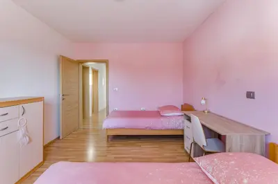 a bedroom with two beds and a wooden table at Počitniška hiša Kapitanovše in Ajdovščina