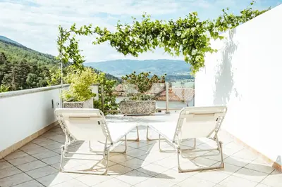 two chairs on a balcony with a view of mountains at Apartma Frigidum in Vipava