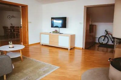 a living room with a table and a tv on the wall at Apartma Frigidum in Vipava