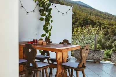 a wooden table and chairs on a patio with a view at Apartma Frigidum in Vipava