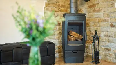 a wood stove in a brick wall with a vase of flowers at Vista Larix Chalet in Ljubno