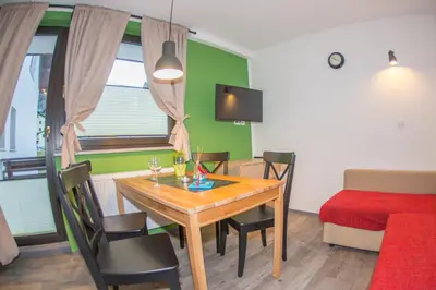 a dining room with a table and chairs and a bed at Apartments Helena Kranjska Gora in Kranjska Gora