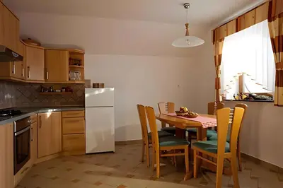 a kitchen with a table with chairs and a white refrigerator at Holiday home in Otocec - Kranjska (Krain) 26040 in Otočec