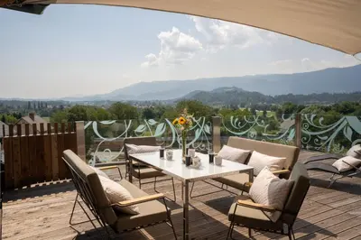 a patio with a table and chairs on a deck at Aparthotel Hom at Vintgar in Zgornje Gorje