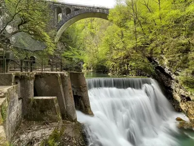 a bridge over a waterfall next to a river at Aparthotel Hom at Vintgar in Zgornje Gorje