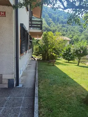 a building with a balcony and a grass yard at Apartma PRI ŠTAJERKI in Most na Soči