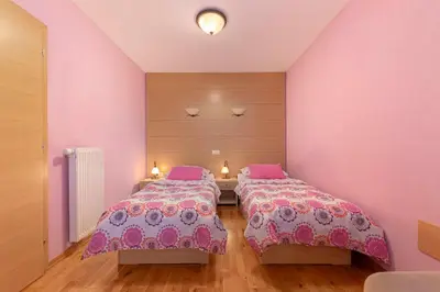 two beds in a room with pink walls and wooden floors at Gostilna Lipan in Gorenja Vas
