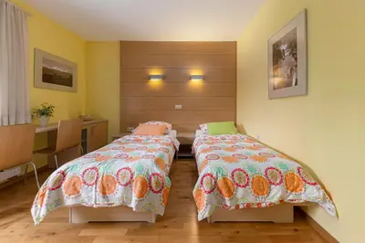a bedroom with two beds and a desk at Gostilna Lipan in Gorenja Vas