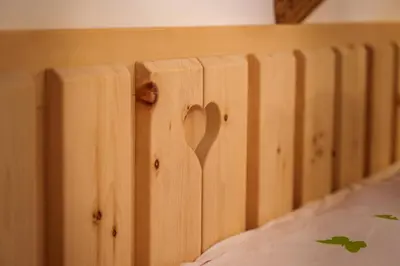 a wooden bed frame with a heart carved into it at Rooms Dreisiebner at the Heart in Zgornja Kungota