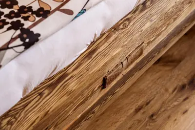 a close up of a wooden bed with a flower on it at Rooms Dreisiebner at the Heart in Zgornja Kungota