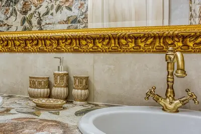 a bathroom with a gold mirror and a sink at Royal Garden in Škofja Loka