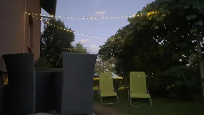 two chairs and a table in a yard with lights at Apartma Tatjana in Žirovnica