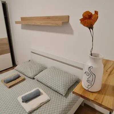 a bed with two pillows and a vase with a flower at Josef apartment, CENTER in Solkan