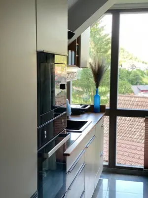 a kitchen with white cabinets and a large window at Lux in Bohinj in Bohinj
