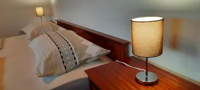a lamp on a wooden table next to a bed at Apartma Helena in Ajdovščina