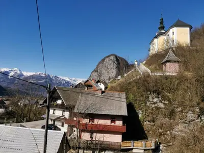 a church on the side of a hill with houses at Apartma Bohinj in Bohinj