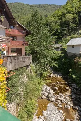 a river in front of a house with a building at Apartma Bohinj in Bohinj