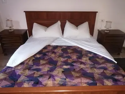 a bed with a quilt on it with two night stands at Silentium Domus doo in Gornje Vreme