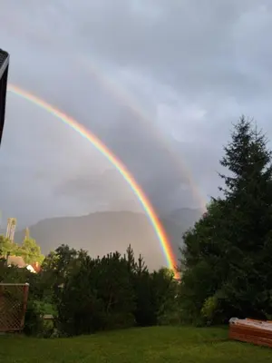 a rainbow in the sky over a field at Sunrise Apartment in Rateče