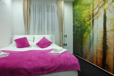 a bedroom with a bed with pink pillows and a painting at Luwiana Suites in Ljubljana