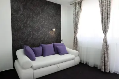 a living room with a white couch with purple pillows at Luwiana Suites in Ljubljana