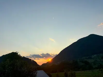 a sunset over a mountain range with the sun setting at Livan Apartment in Tolmin