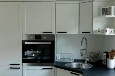 a kitchen with white cabinets and a sink and an oven at Aura Apartments in Žirovnica