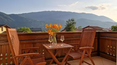 a table and two chairs on a balcony with wine glasses at Apartma Kofol in Kobarid