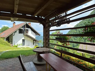 a porch with benches and a table and a house at Apartma Slovenias in Škofja Loka