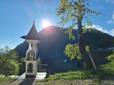 a tower with a cross on it next to a tree at Apartma Slovenias in Škofja Loka