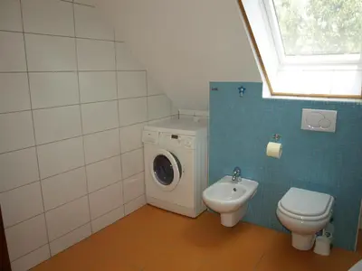 a bathroom with a washing machine and a toilet at Apartment VISOTA in Ptuj