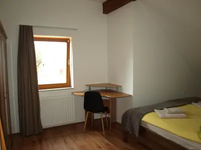 a bedroom with a bed and a desk and a window at Apartment VISOTA in Ptuj