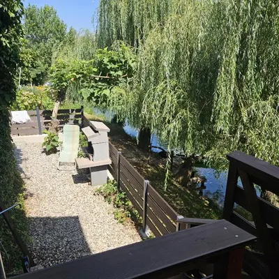 a park bench next to a river with a bridge at Apartment Kostanjevica na Krki in Kostanjevica na Krki