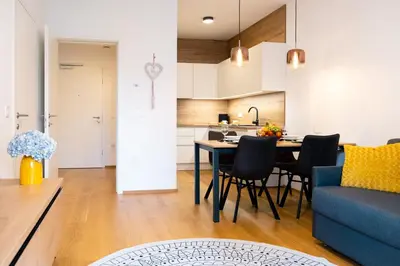 a kitchen and living room with a blue couch and a table at Masarykova Residence - Modern 1-Bedroom in City Center & Free Parking in Ljubljana