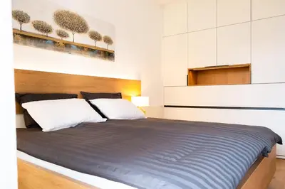 a bedroom with a large bed with white walls at Masarykova Residence - Modern 1-Bedroom in City Center & Free Parking in Ljubljana