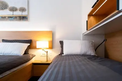 a small bedroom with two beds and a lamp at Masarykova Residence - Modern 1-Bedroom in City Center & Free Parking in Ljubljana