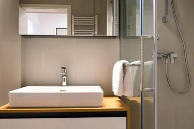 a bathroom with a white sink and a shower at Masarykova Residence - Modern 1-Bedroom in City Center & Free Parking in Ljubljana