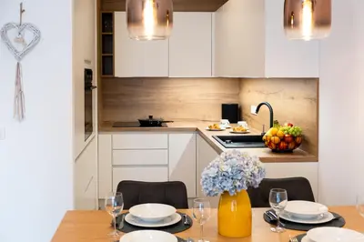 a kitchen with a table with chairs and a kitchen with white cabinets at Masarykova Residence - Modern 1-Bedroom in City Center & Free Parking in Ljubljana